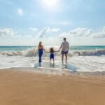 A family holiday hands on the shoreline of a sunny beach