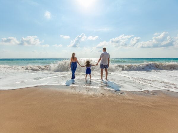 A family holiday hands on the shoreline of a sunny beach