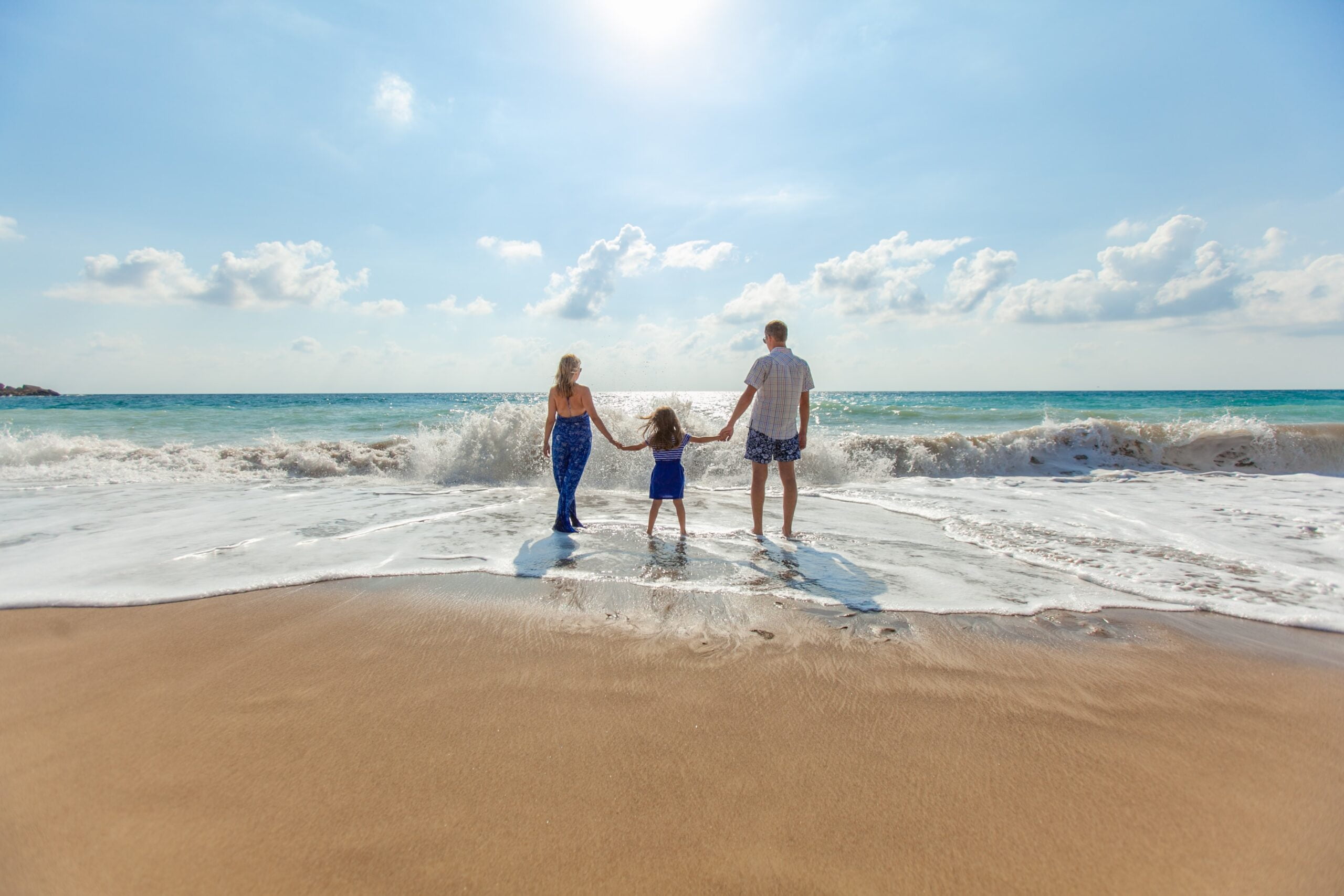 A family holiday hands on the shoreline of a sunny beach