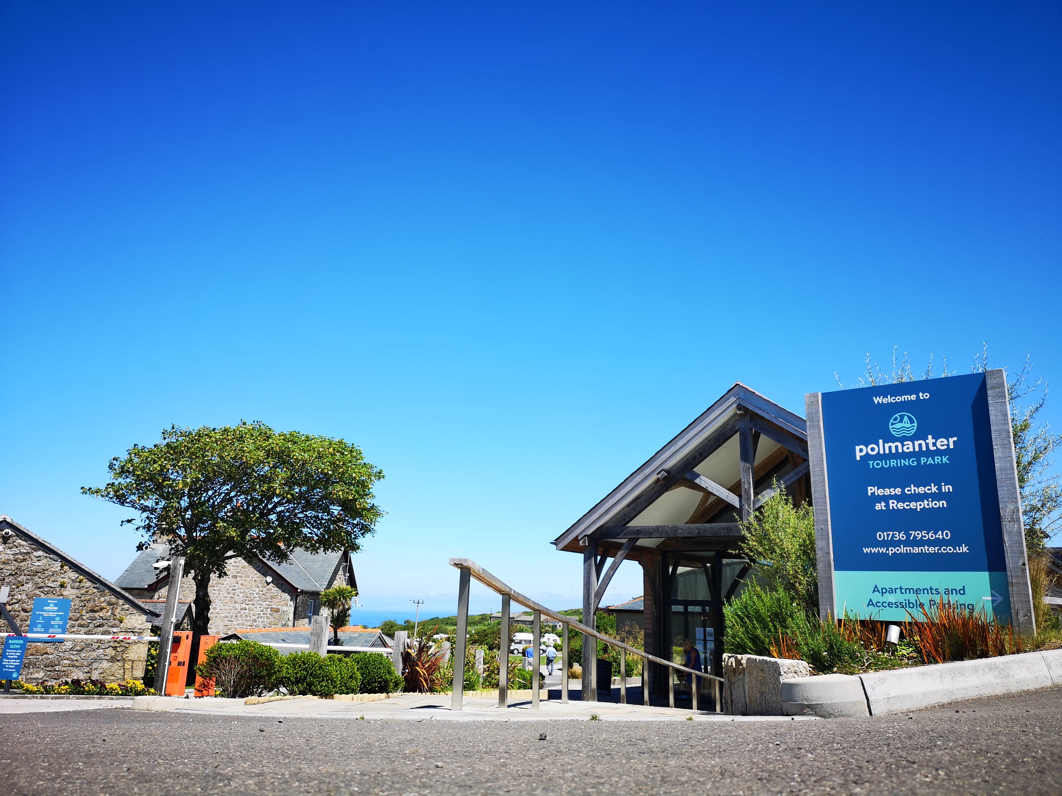 Polmanter sign in front of reception building with bright blue sky and the sea in the background