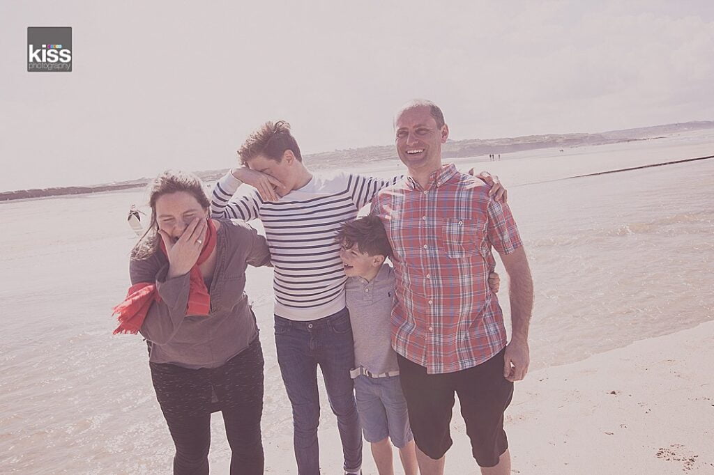 Family of four on the beach giggling during a family photoshoot in st ives