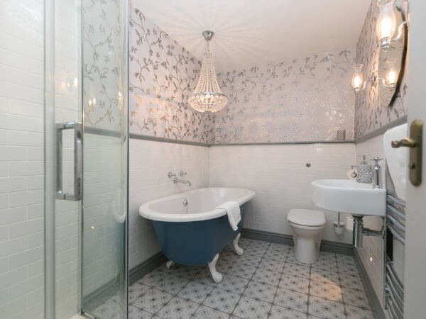 Bedroom Two's en-suite with chandelier over roll top bath in Polmanter Touring Park's self-catering holiday cottage St Ives