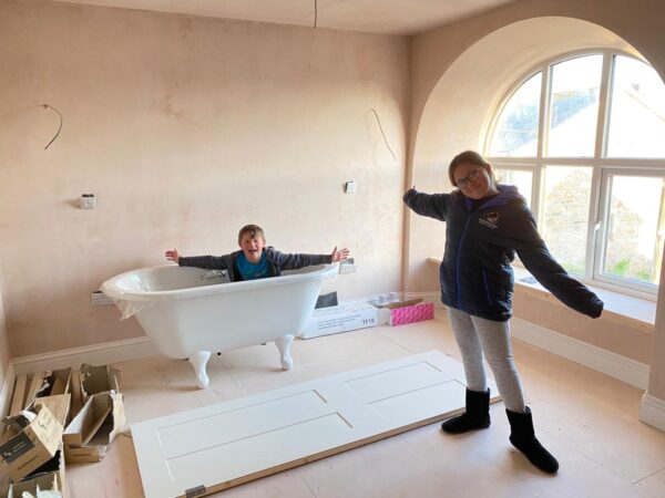 Kerenza and William showcase the roll top bath going into bedroom one's ensuite in the Polmanter holiday cottage renovation
