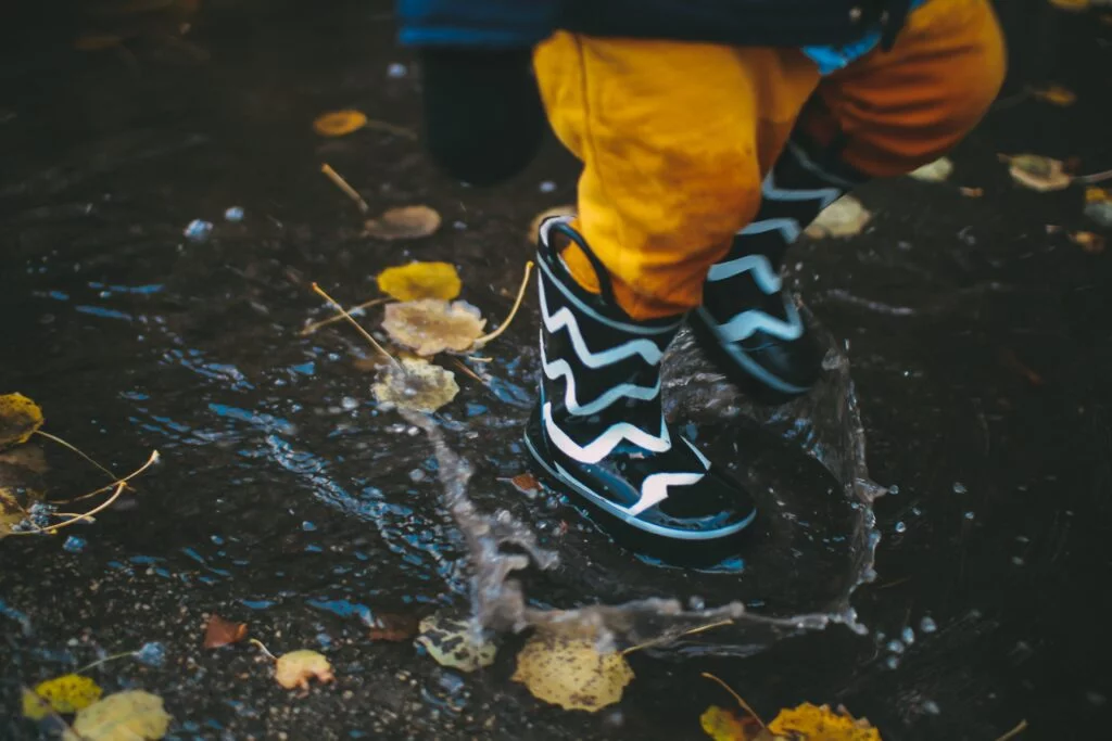 Child splashing in the puddles on a rainy day in Cornwall