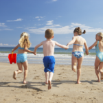 Four children running towards the sea on a sunny day in West Cornwall