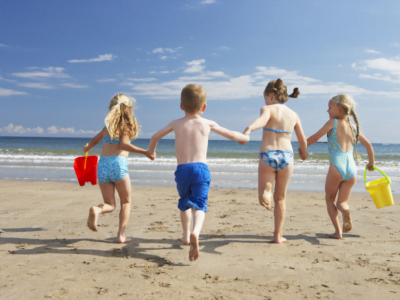 Four children running towards the sea on a sunny day in West Cornwall