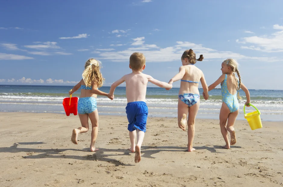 Four children running towards the sea on a sunny day in West Cornwall