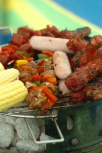 Close up of meat and corn on the cob cooking on a BBQ