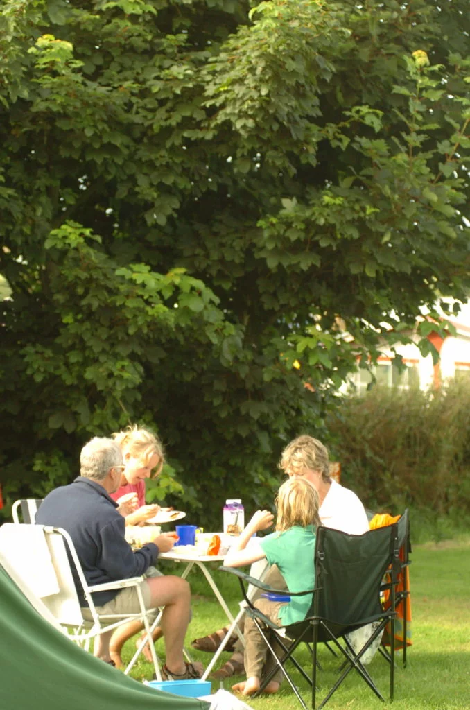 Family enjoying a meal on table and chairs outside their tent
